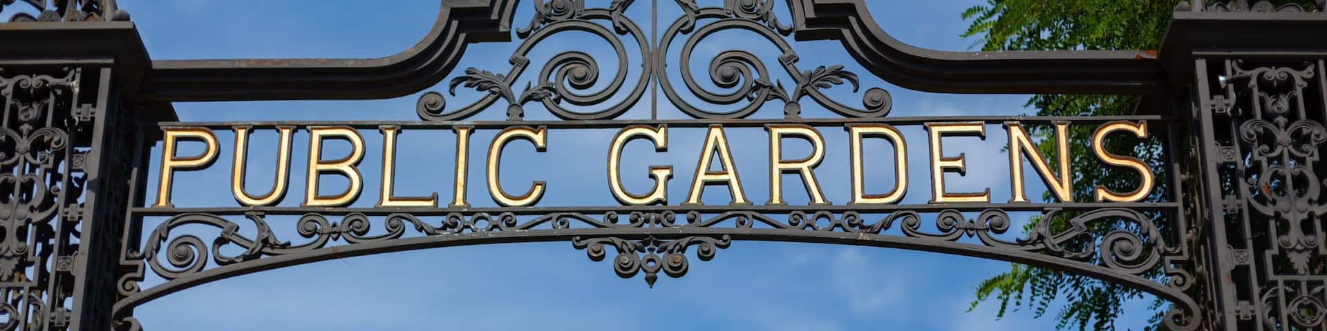 Una ornamentada puerta de metal con la inscripción 'PUBLIC GARDENS' en letras doradas.
