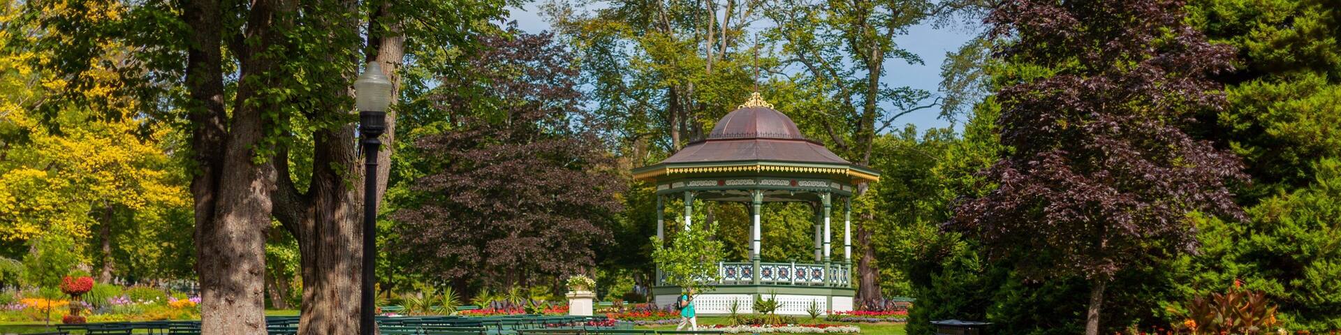Un kiosque dans un parc, entouré d’arbres et de bancs.