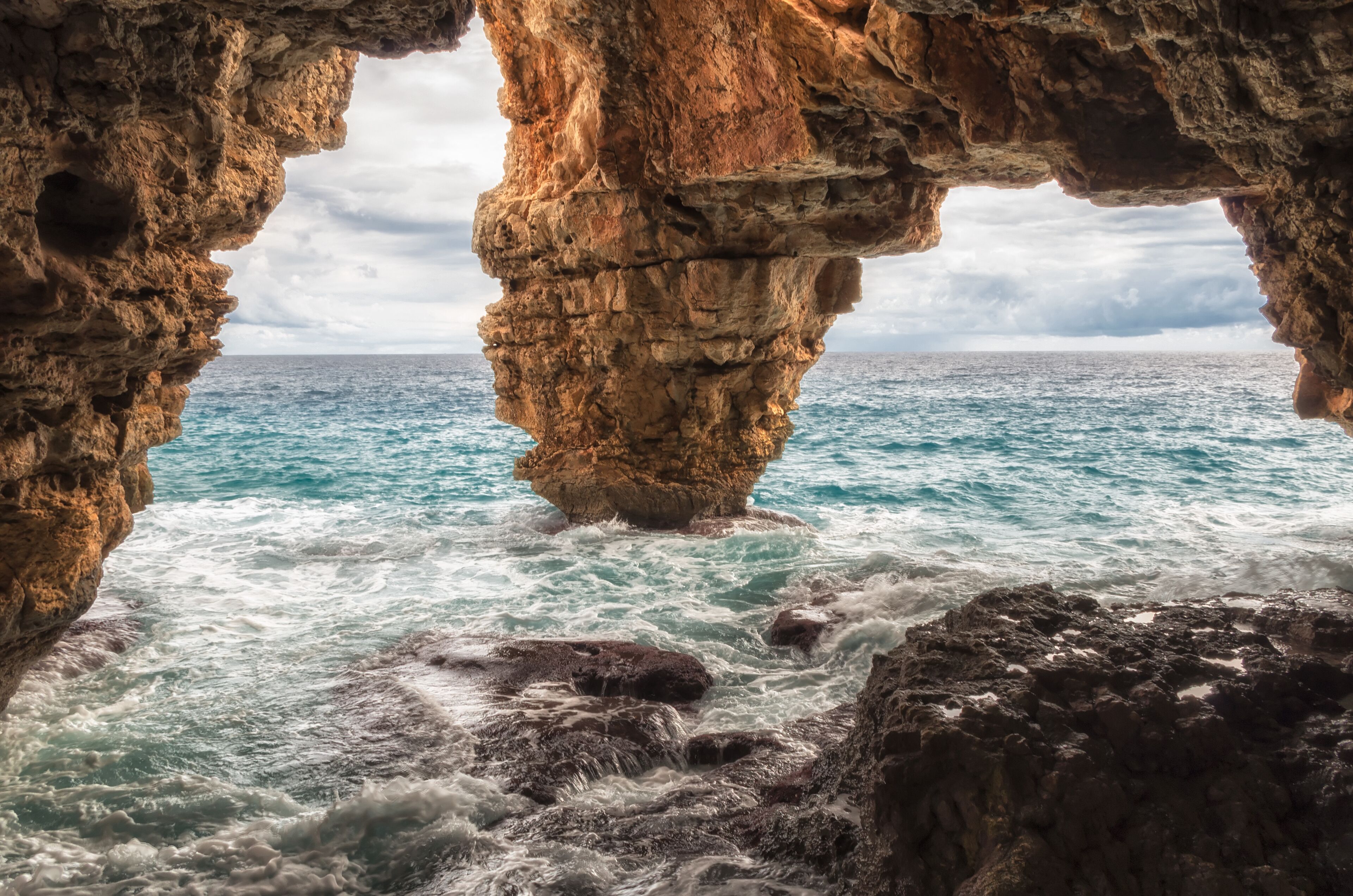 A rocky coastline with a natural arch formation and the ocean.