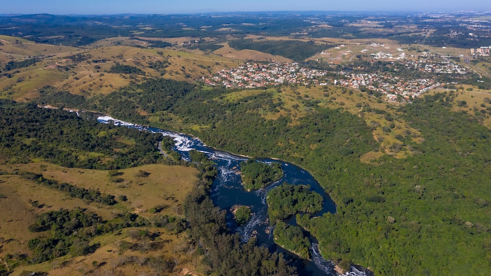 A river winding through a hilly landscape with a town and forested areas.