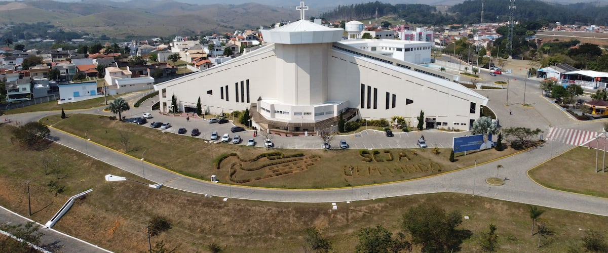 A large white church with a cross on top, surrounded by a parking lot and a road.