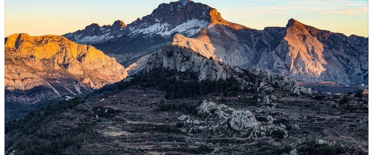 A mountainous landscape with rugged peaks and terraced fields.