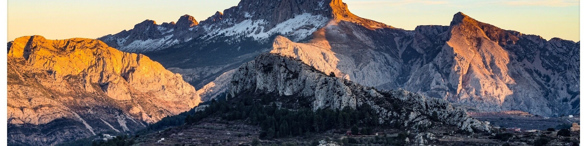 A mountainous landscape with rugged peaks and terraced fields.