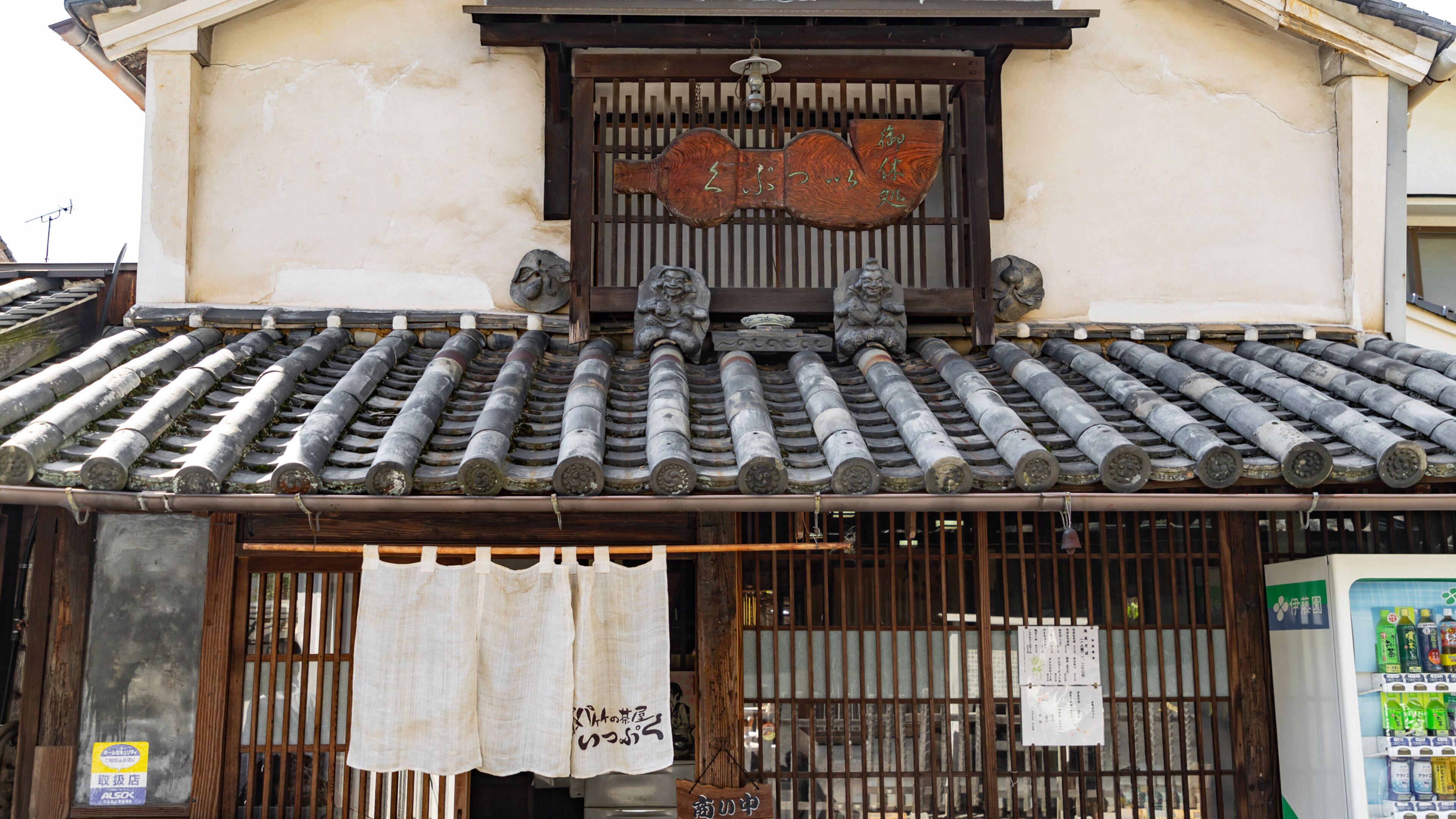 A traditional Japanese building with a tiled roof, wooden beams, and a sign with Japanese characters.