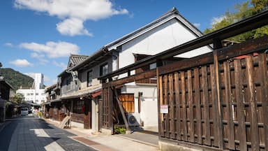 Une rue typique du Japon, avec ses clôtures en bois, ses bâtiments aux toits couverts de tuiles et un ciel d’un bleu éclatant.