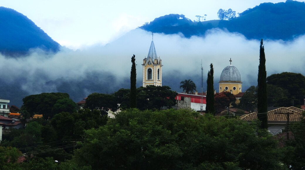 Large image of a beautiful misty mountain landscape in a small town called Joanopolis in the countryside of Brazil. Catholic church clock and bell tower view among foggy mountains and stunning nature