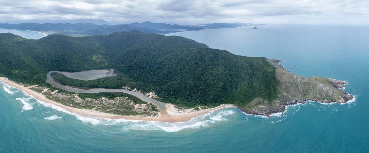 An aerial view of a tropical island with a winding road, a beach, and surrounding ocean.