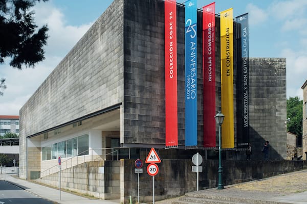 Ein modernes Gebäude mit einer Steinaußenwand und bunten Bannern.