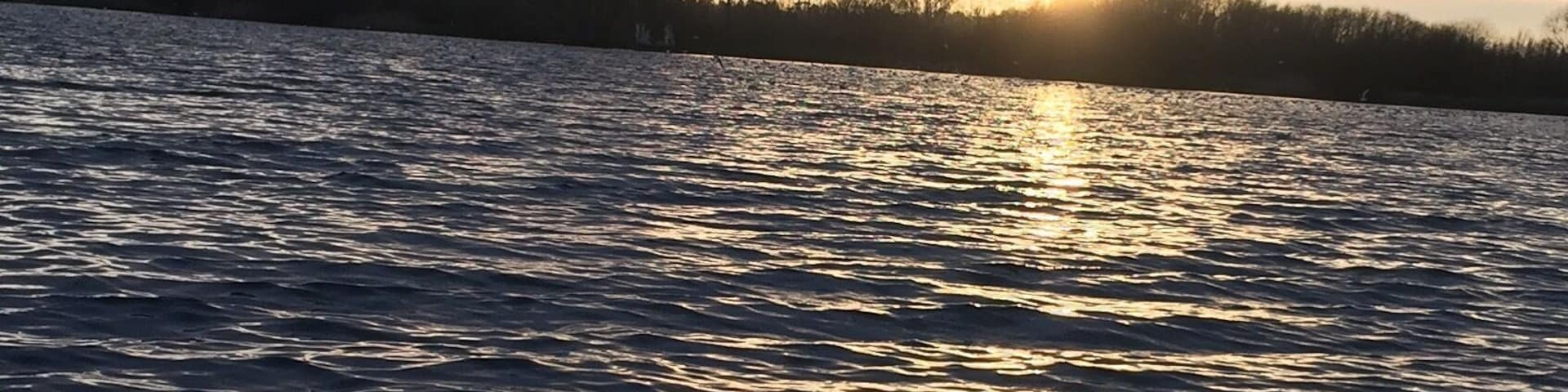 Um pôr do sol sobre a água, refletindo o céu.