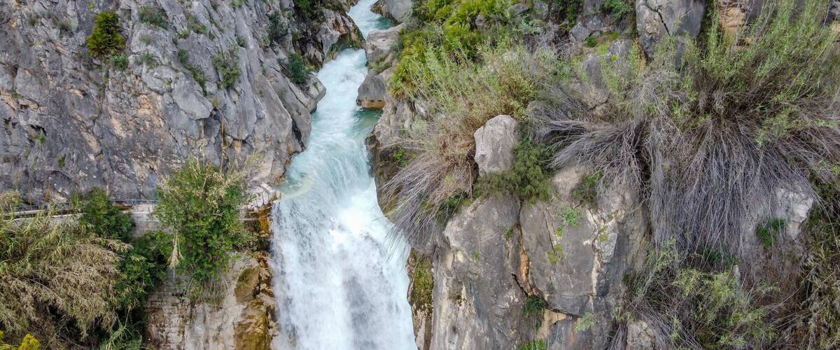 A waterfall cascading down a rocky cliff surrounded by greenery.
