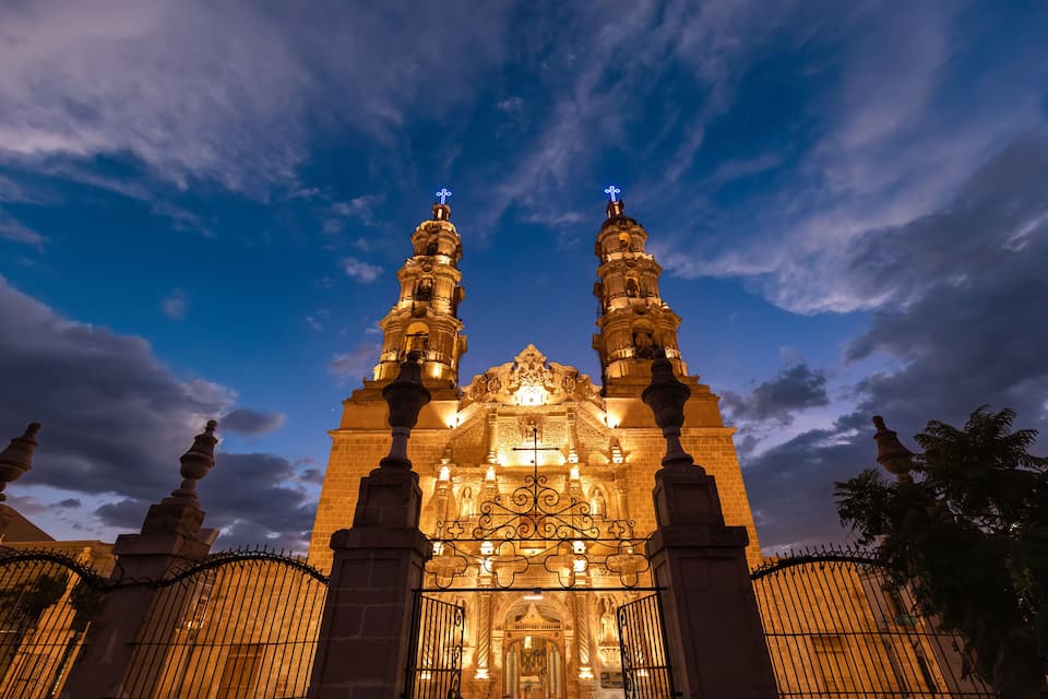 A historic church with two tall towers and a large entrance gate.