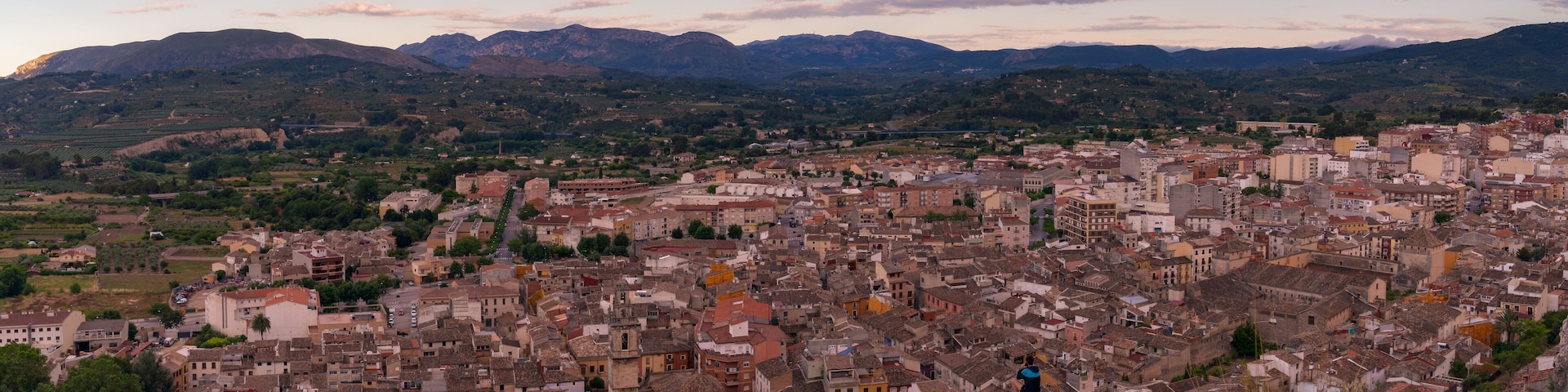 A panoramic view of a historic town with a mountainous backdrop.