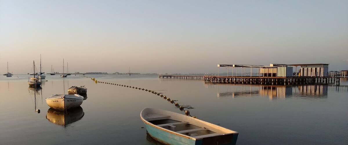 A calm harbor with boats anchored near a wooden pier.