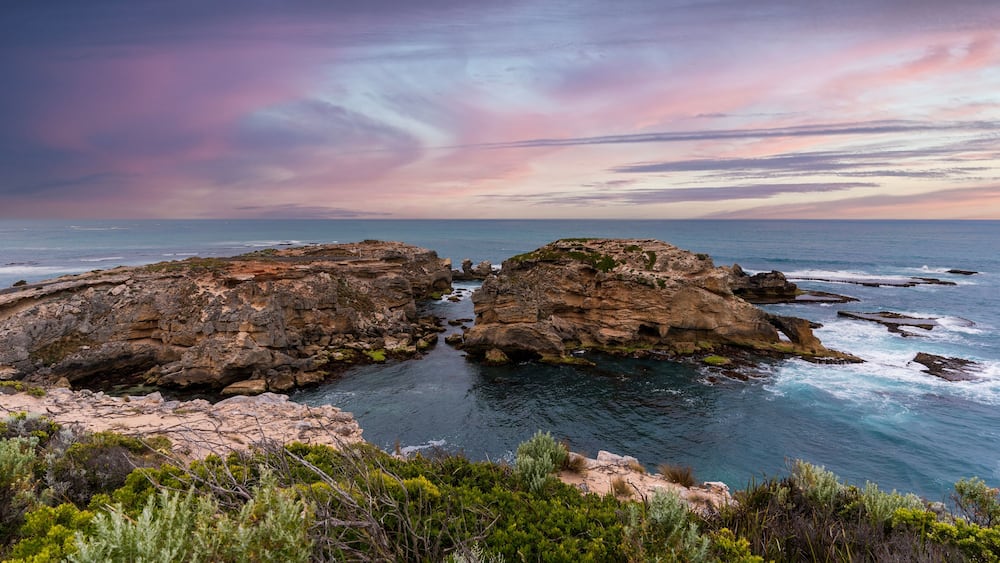 Un paysage côtier caractérisé par des formations rocheuses et une mer d’un bleu limpide.