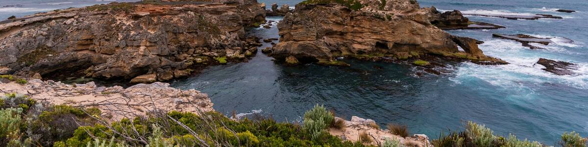 A coastal landscape with rocky formations and clear blue sea.