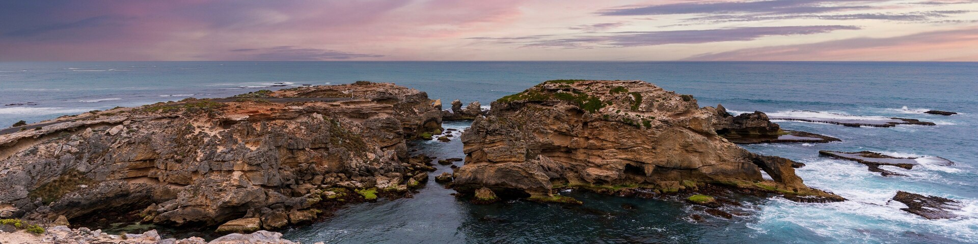 Paisagem costeira com formações rochosas e mar azul cristalino.