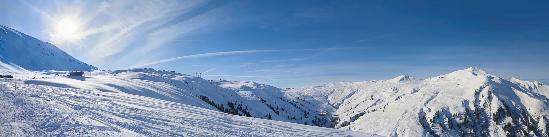 A snow-covered mountain landscape with ski slopes, ski lifts, and a clear blue sky.