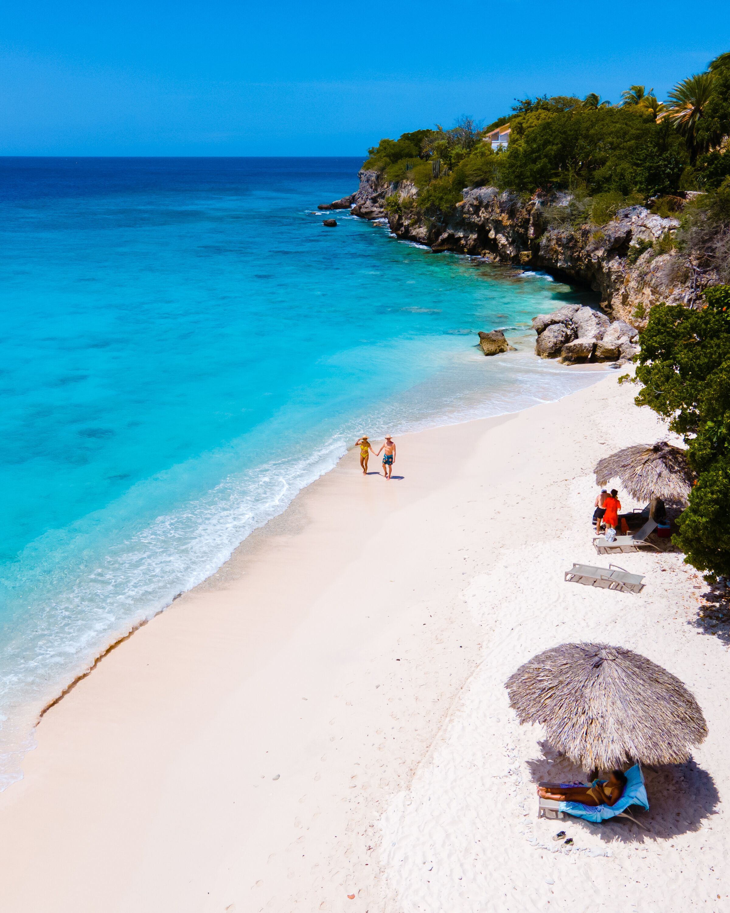 Playa Kalki Beach Caribbean island of Curacao, Playa Kalki in Curacao, white beach with a blue turqouse colored ocean. Drone aerial view of a couple of men and women at the beach