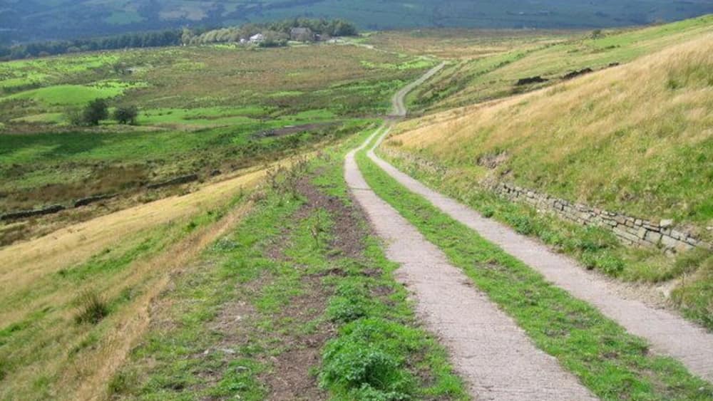 A winding country road through rolling hills with fields on either side.