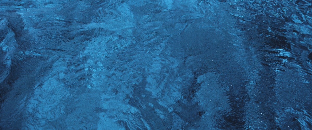 A clear blue sea with a small island in the distance.