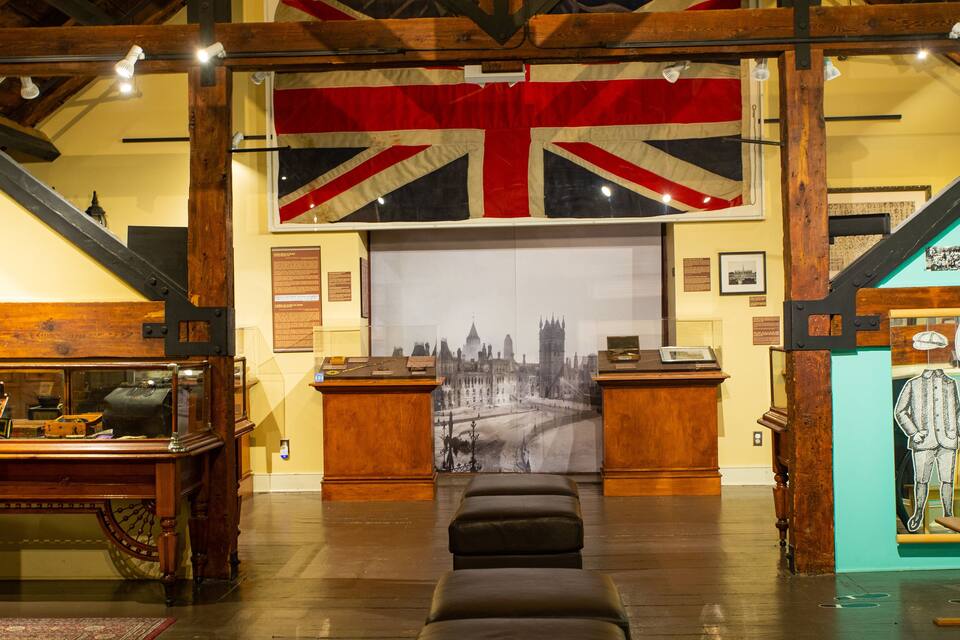 A room with a large Union Jack flag, wooden furniture, and a cityscape painting.