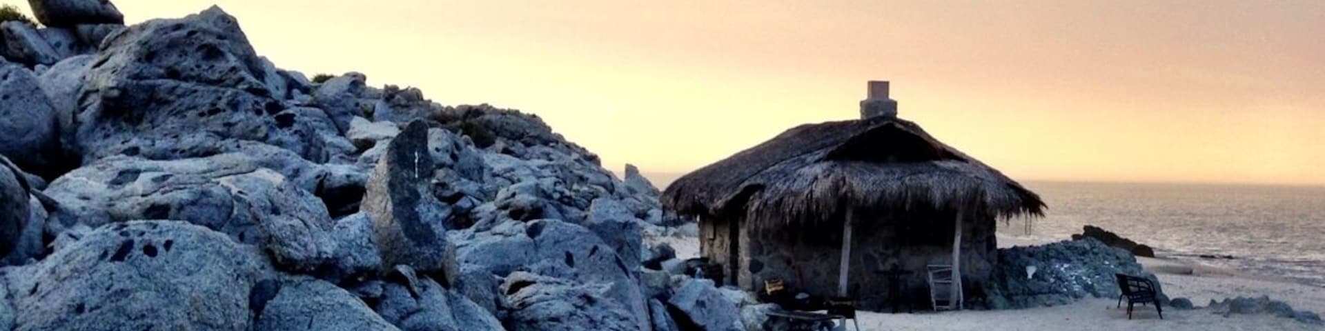 The stone sleeping cabin. Spectacular place to cozy up for a night on the beach. Complete with wood for bonfire, solar power, stove for AM coffee, and waves crashing at your door. A most hidden gem, off the grid. About $150/night.