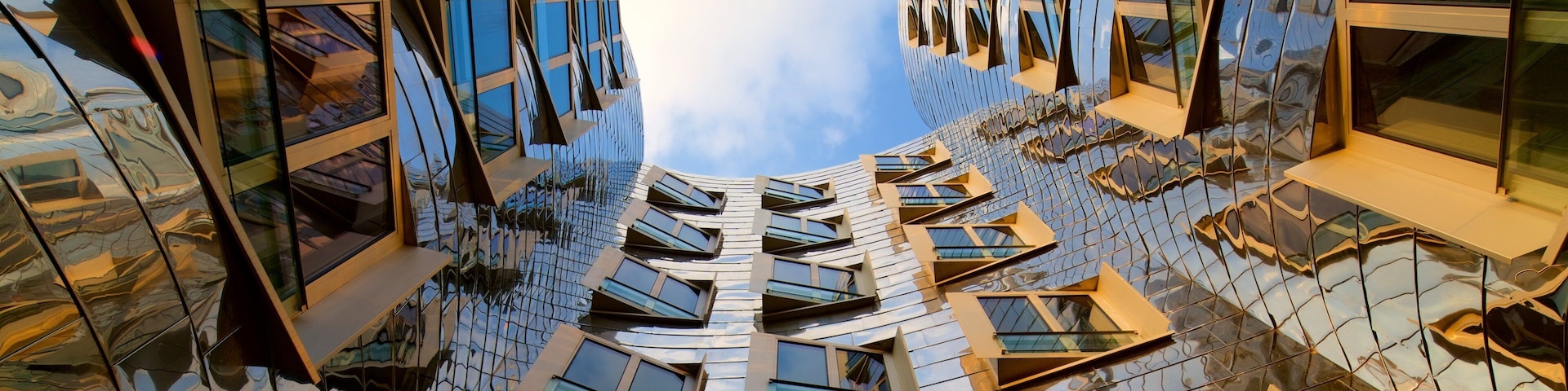 A modern architectural building with a reflective glass facade and multiple windows.