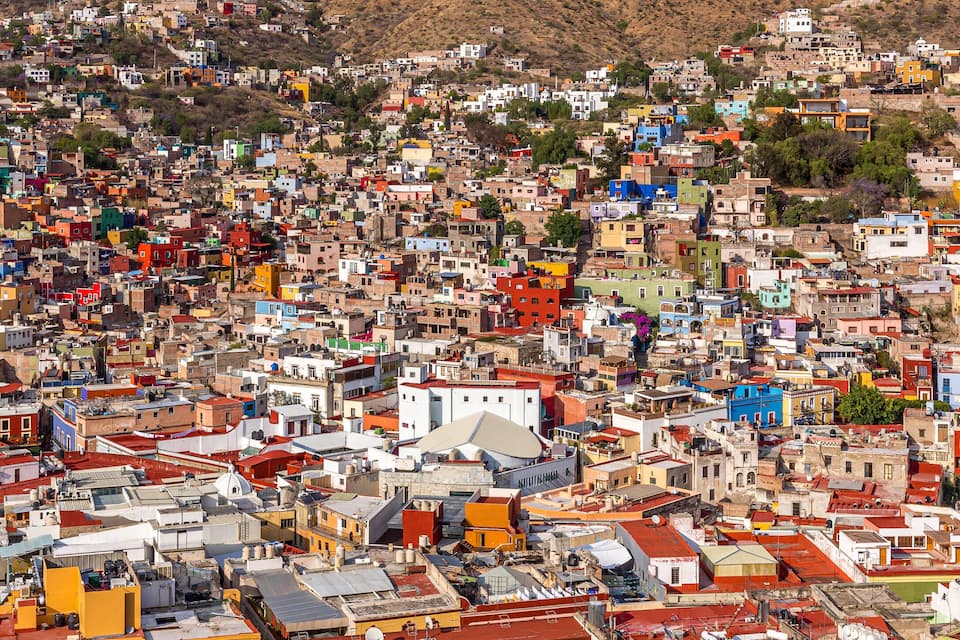 Un área urbana densamente poblada con edificios coloridos y un paisaje montañoso al fondo.
