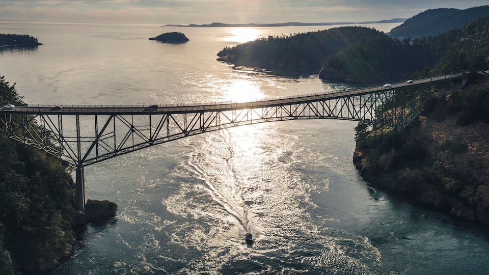 A suspension bridge over a river surrounded by dense forests and hills.
