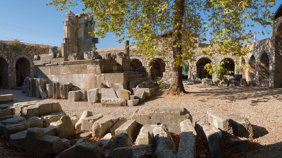Ancient ruins with stone blocks, arches, and a tower.