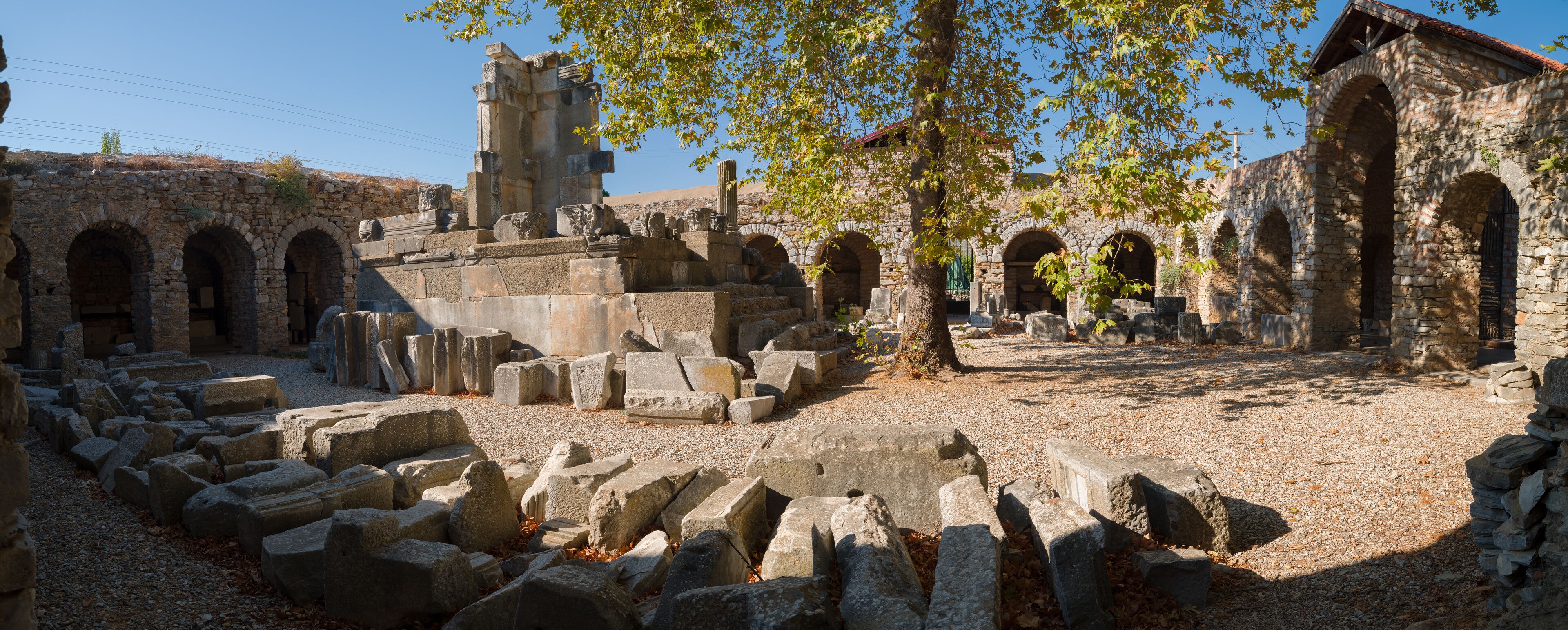 Ancient ruins with stone blocks, arches, and a tower.