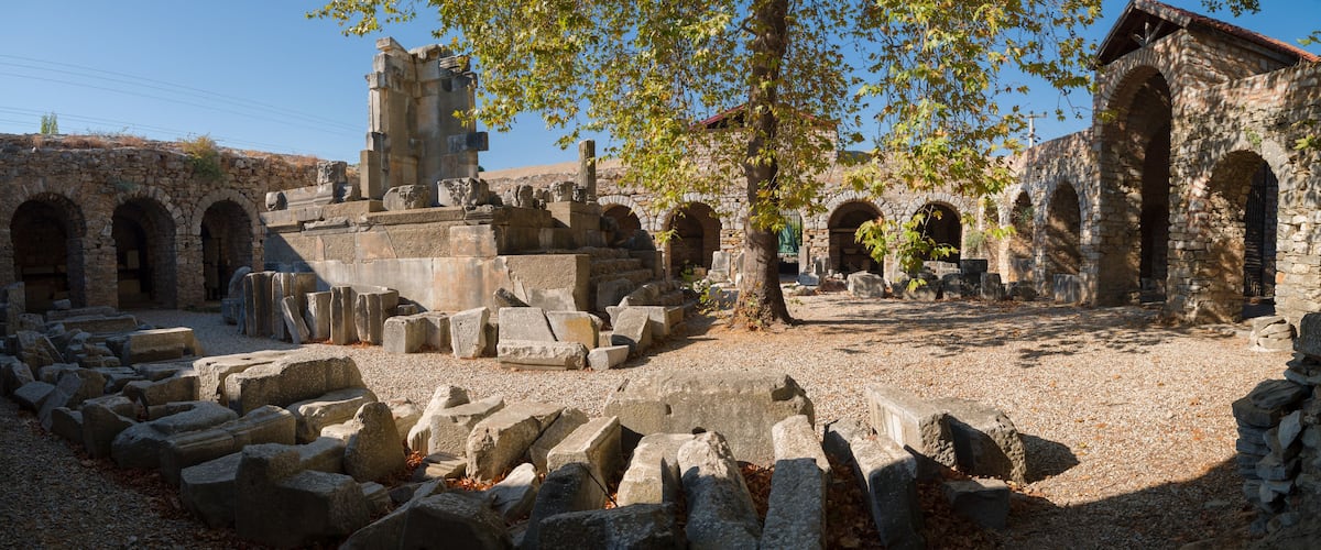 Ancient ruins with stone blocks, arches, and a tower.