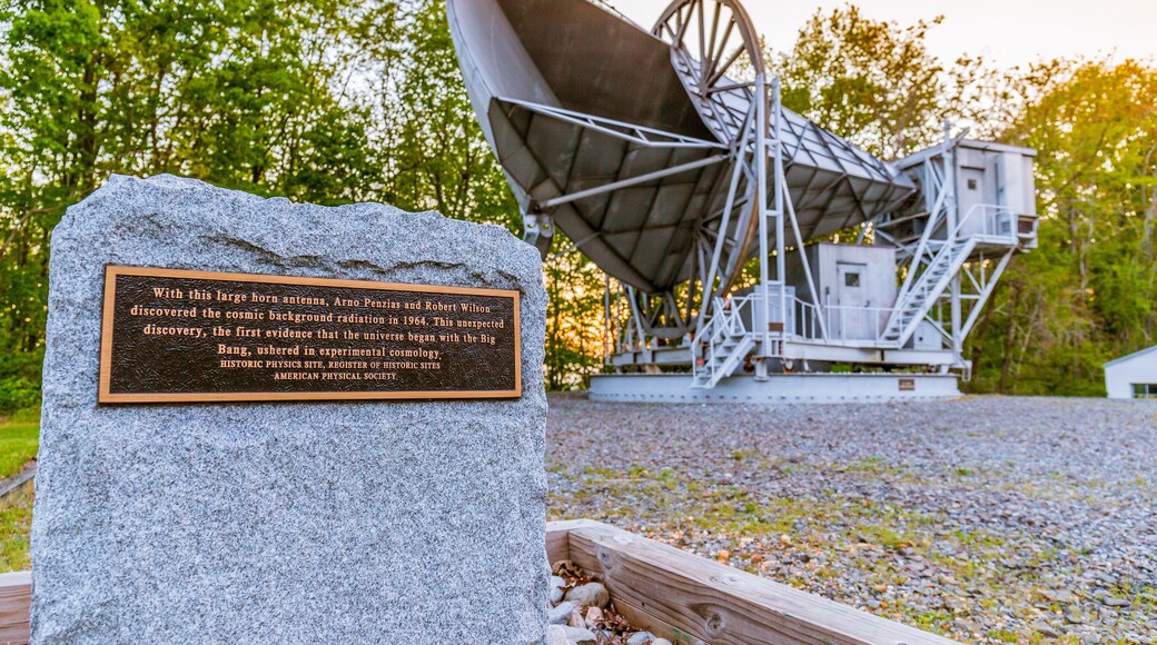 A large radio telescope with a plaque in front.