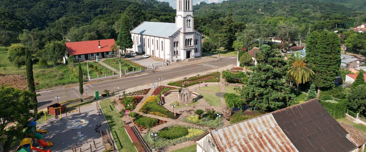 A church with a tall steeple, surrounded by lush greenery and hills.