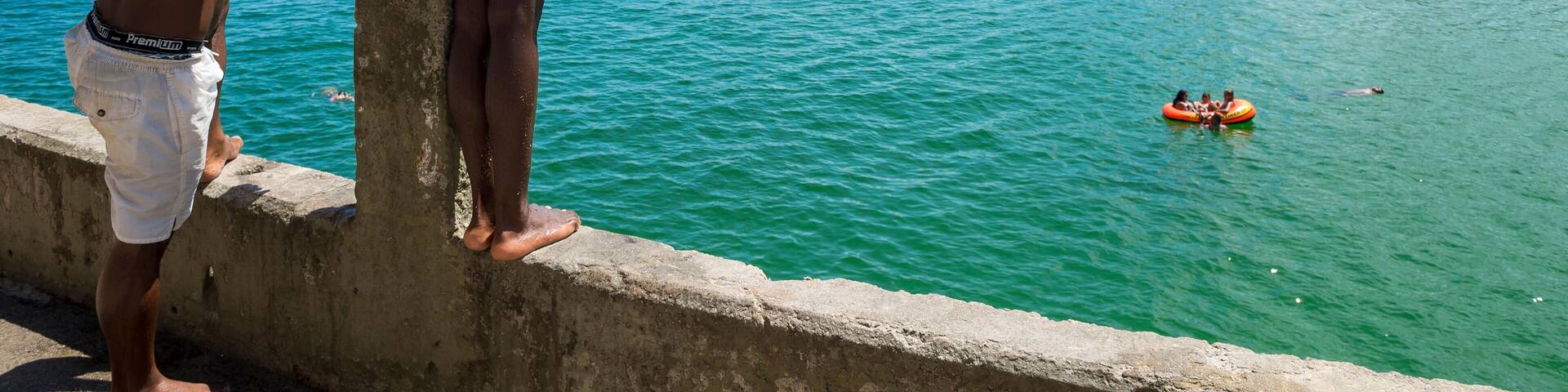 RIO DE JANEIRO - FEBRUARY 27, 2016: Young Brazilians gather to dive from the ledge at Leme, at the far end of Copacabana Beach.