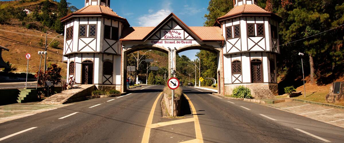 A road leading to a building with two towers and a sign reading 'Aguas Lindas Capital Termal do Brasil.'