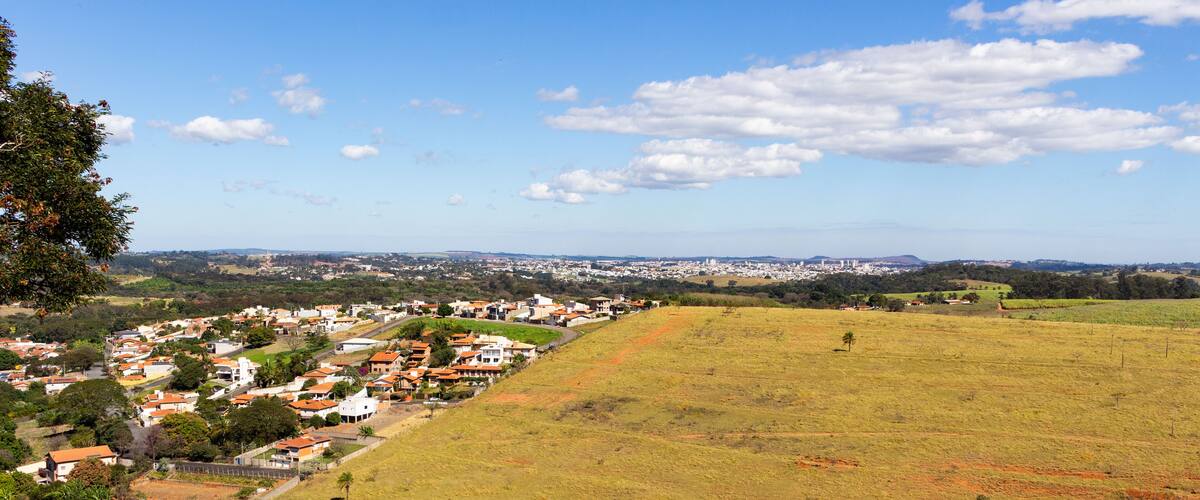A town nestled in a valley with a large open field and a hill with houses.