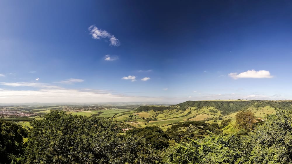 Ein Panoramablick auf ein saftig grünes Tal mit sanften Hügeln und blauem Himmel.