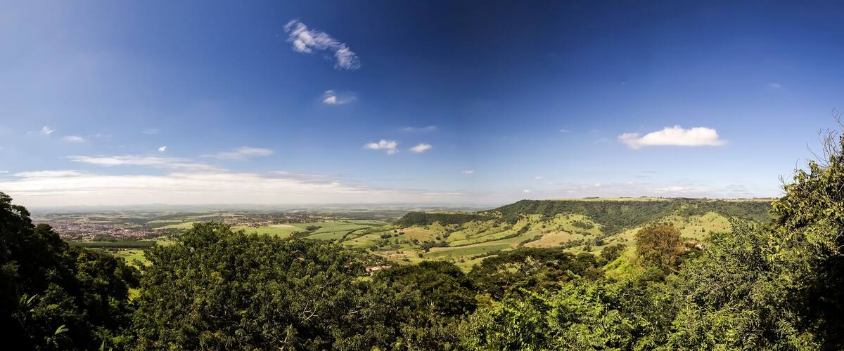 A panoramic view of a lush green valley with rolling hills and a clear blue sky.
