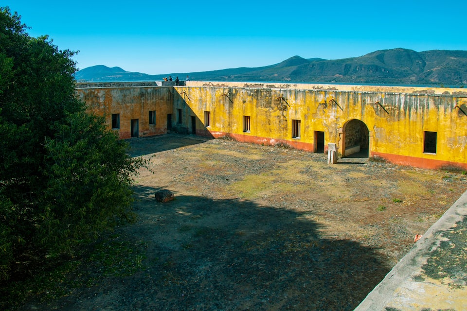 An old yellow building with arched doorways and a clear blue sky in the background.