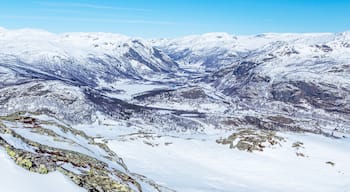A snow-covered mountain range with a valley and a lake.