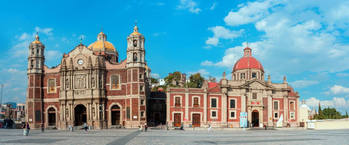 A historic cathedral with two domes and bell towers, surrounded by a plaza.