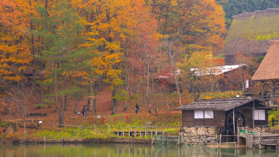 A serene autumn landscape with a wooden house by a lake, surrounded by vibrant fall foliage.
