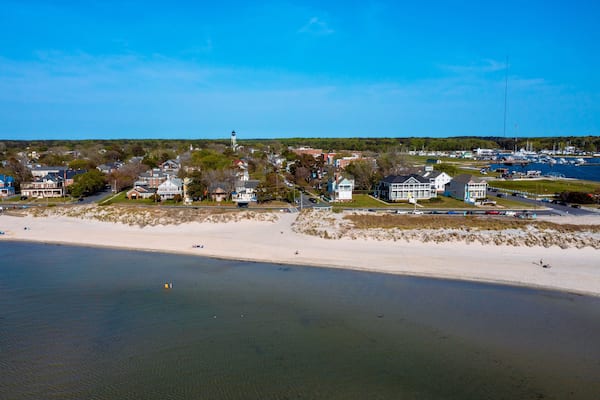 Une ville côtière dotée d’une plage de sable, de maisons et d’un phare.