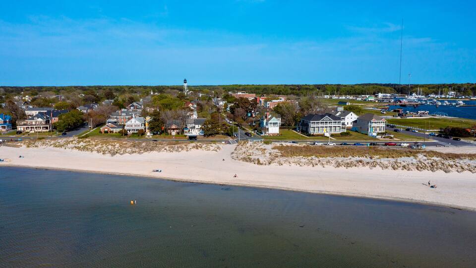 A coastal town with a sandy beach, houses, and a lighthouse.