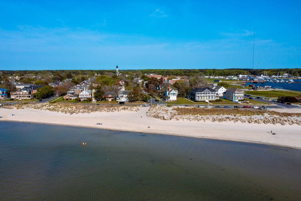 Une ville côtière dotée d’une plage de sable, de maisons et d’un phare.