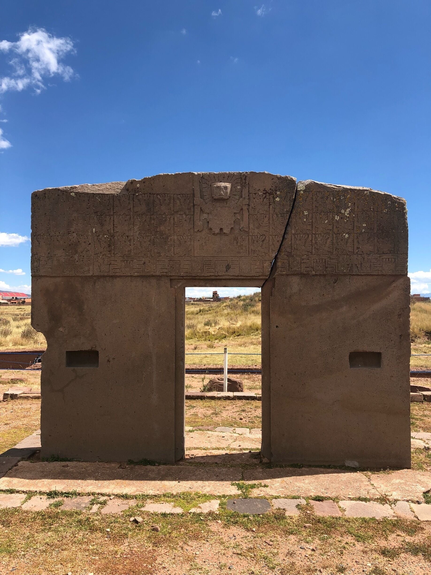 An ancient stone archway with carvings, set against a clear blue sky.