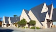 A modern building with a unique geometric design, featuring triangular roofs and beige walls.