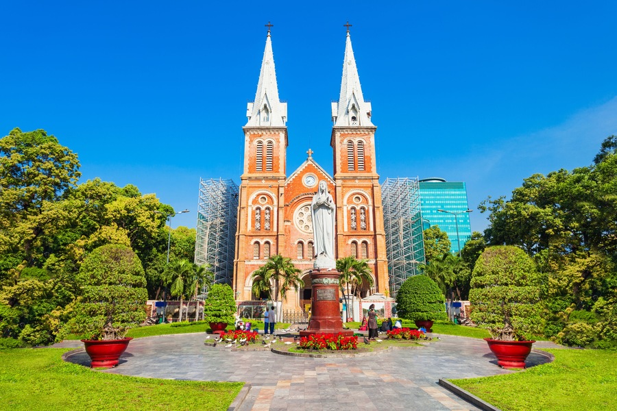 A large church with two tall spires, surrounded by well-maintained gardens and palm trees.