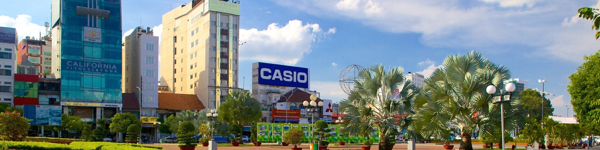 Uma praça urbana com um letreiro Casio, um hotel Queen Ann e um centro de fitness.